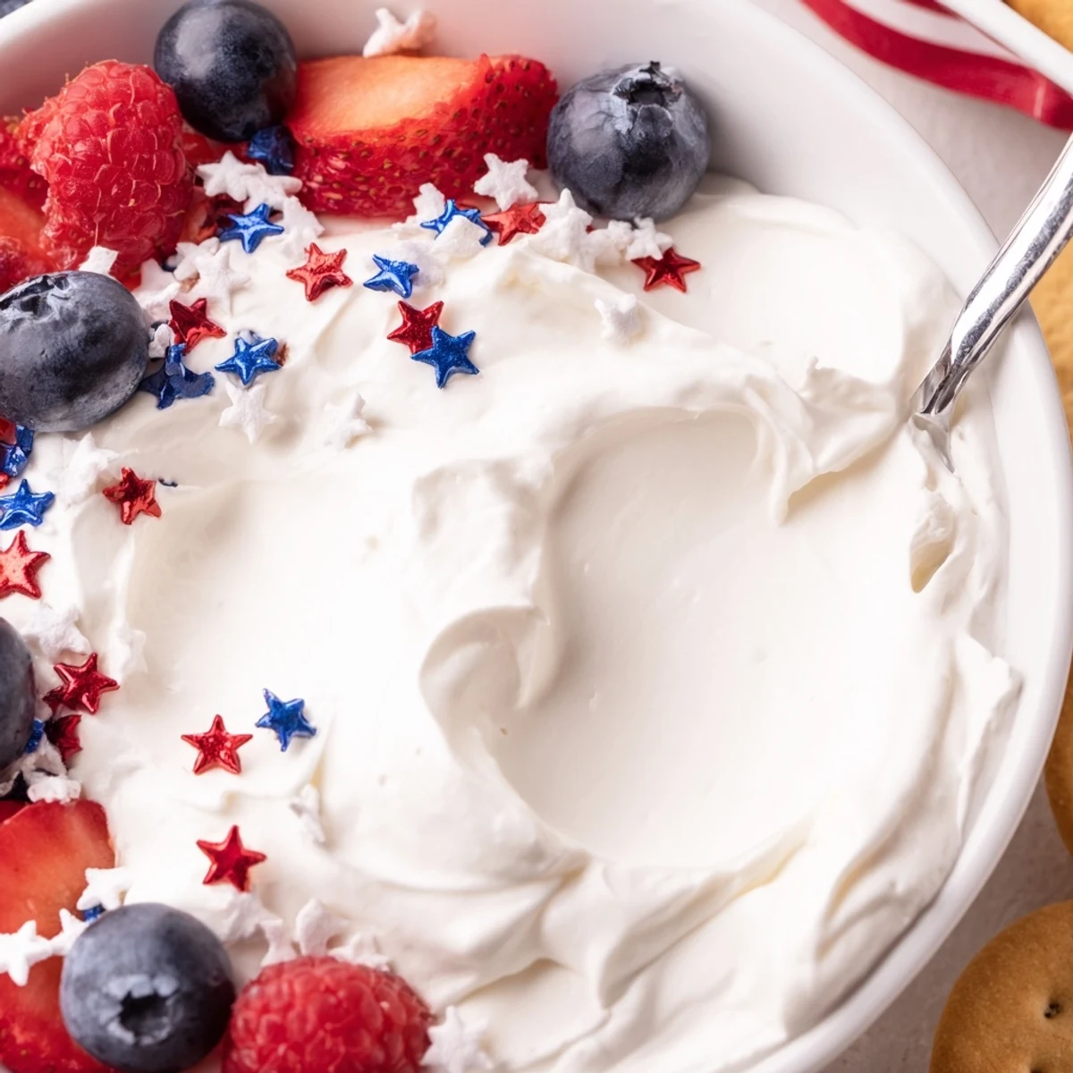 Creamy Star Spangled Cheesecake Dip topped with fresh berries and sprinkles