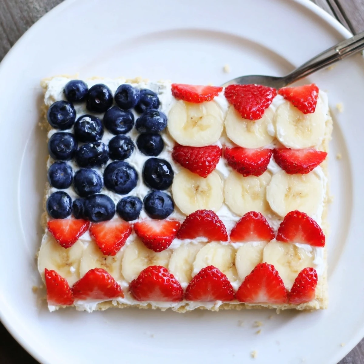 Sliced strawberries and bananas striped on American Flag Fruit Pizza, chilled.