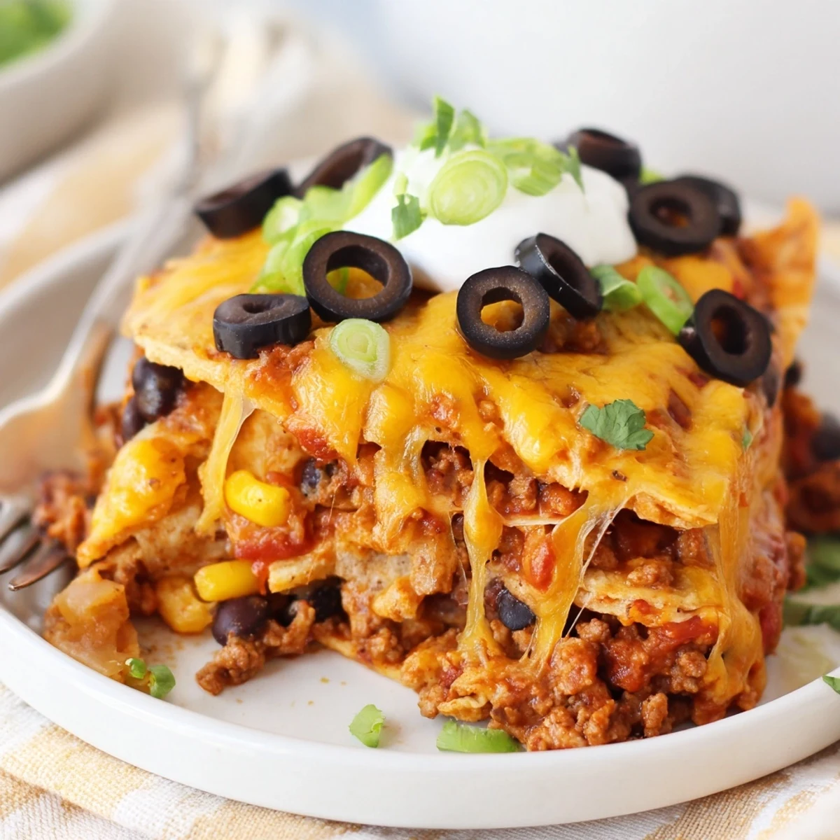 Baked Cheesy Nacho Casserole layered with seasoned beef, beans, bubbling golden cheese