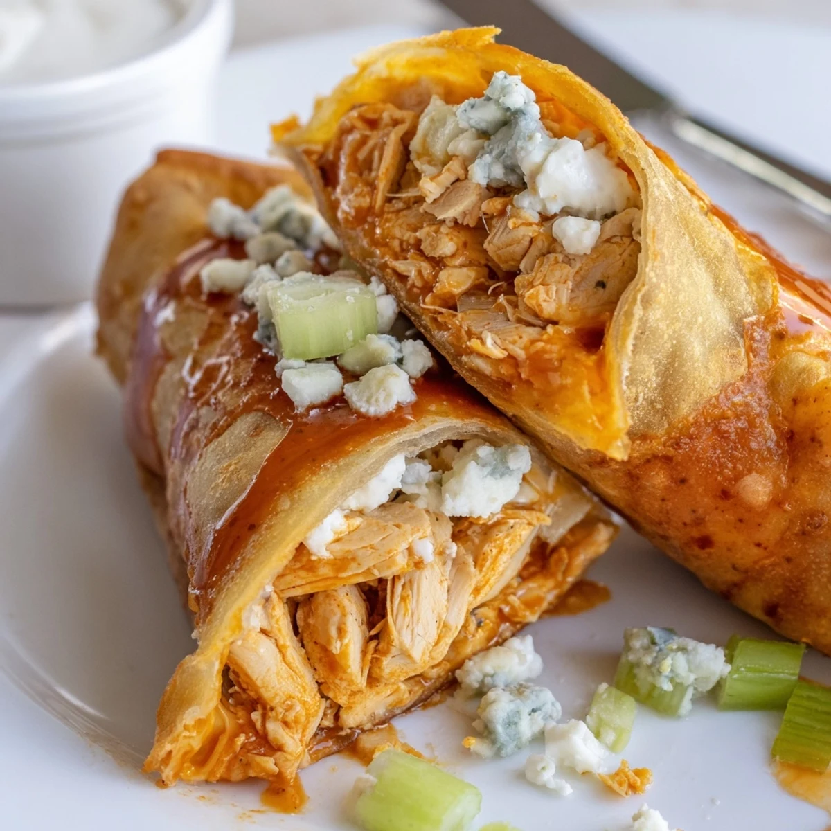 Crispy Buffalo Chicken Egg Rolls piled on plate with ranch dipping sauce