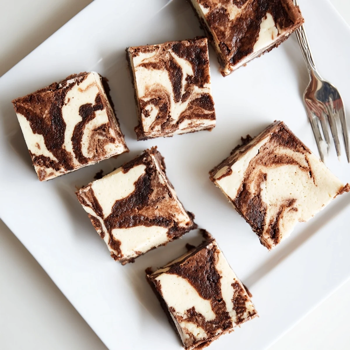 Sourdough cheesecake brownie bars with marbled cream cheese swirls on a white plate