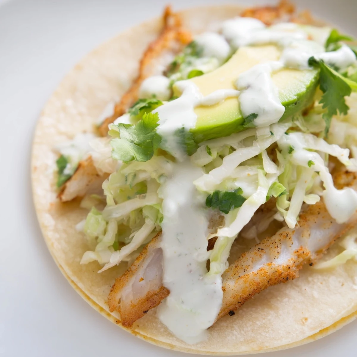 Golden baked cod fish tacos piled high with colorful cabbage slaw and creamy lime drizzle
