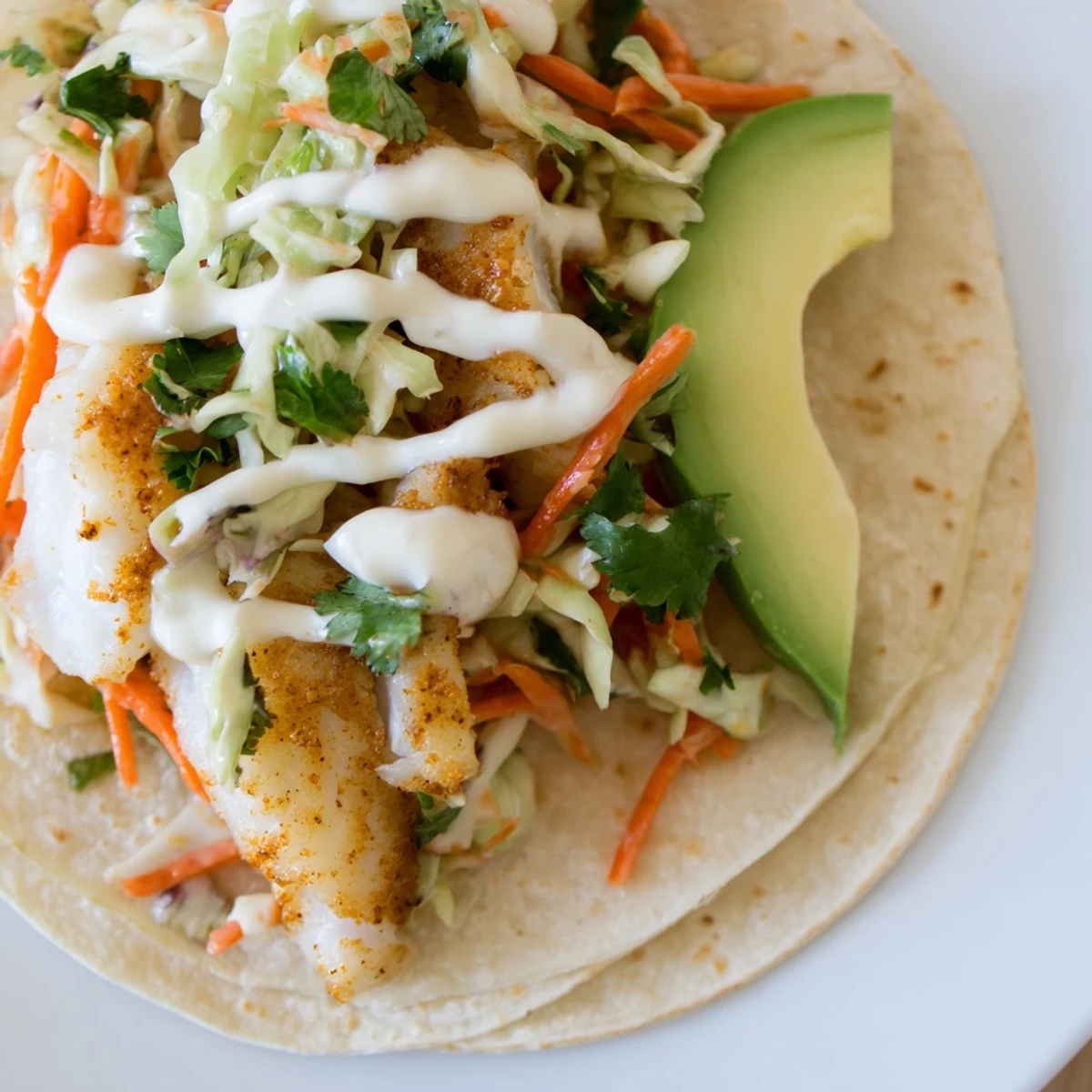 Warm corn tortillas cradle tender baked cod fish tacos topped with zesty lime crema