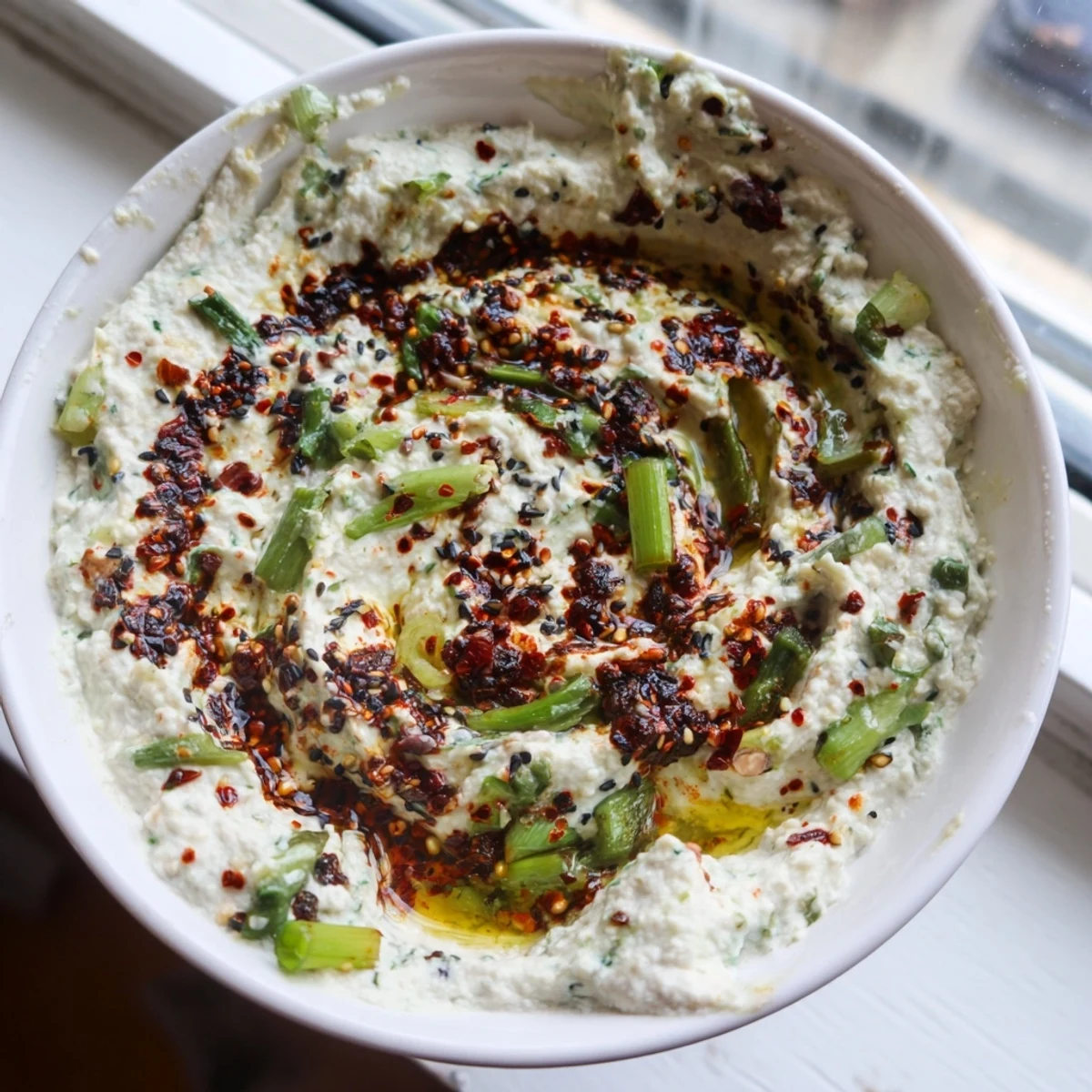 Smoky charred scallion and chili crisp dip served alongside crispy tortilla chips