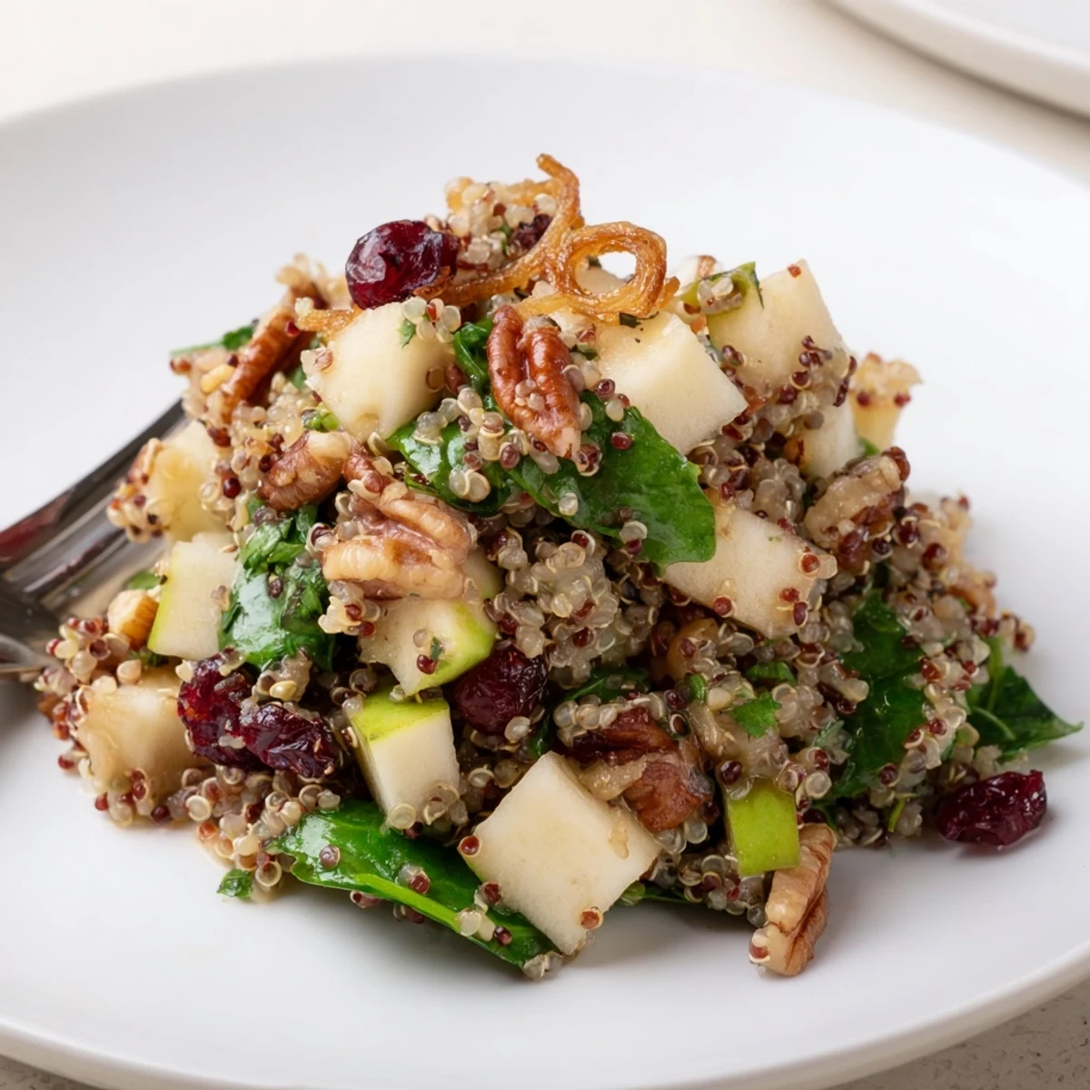 Honey mustard quinoa apple salad topped with golden crispy shallots on a rustic plate
