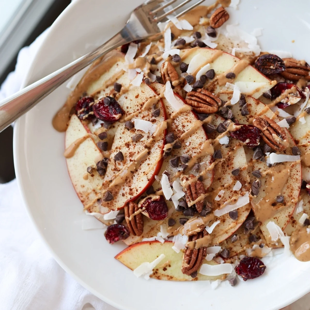 Golden apple slices layered with crunchy nuts and sweet cinnamon tahini drizzle nachos