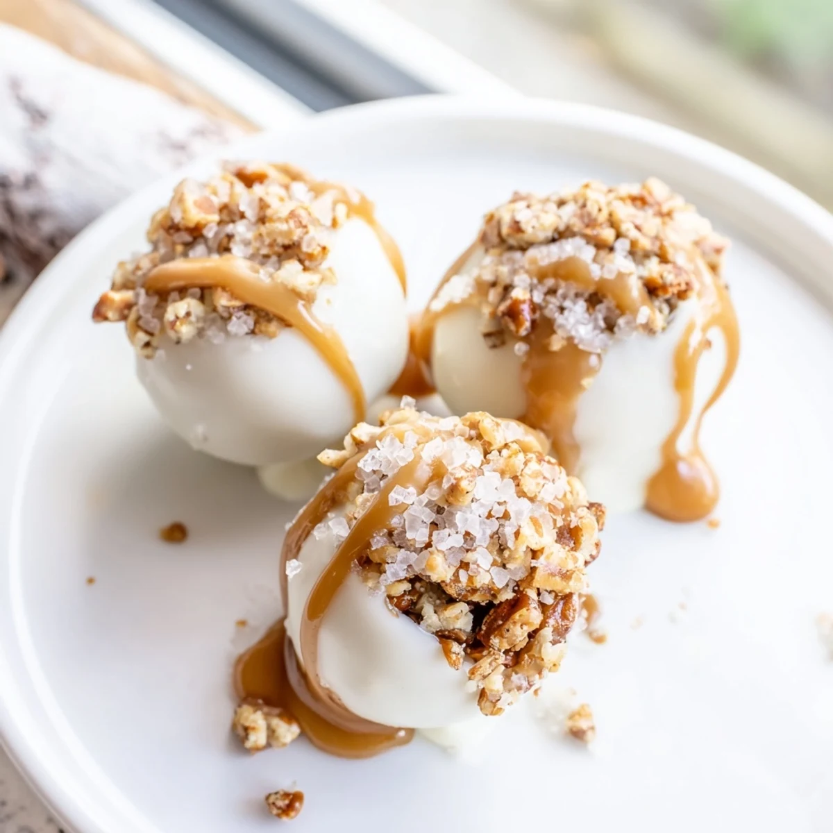 Bite sized salted caramel pretzel cheesecake balls garnished with crushed pretzels and flaky sea salt