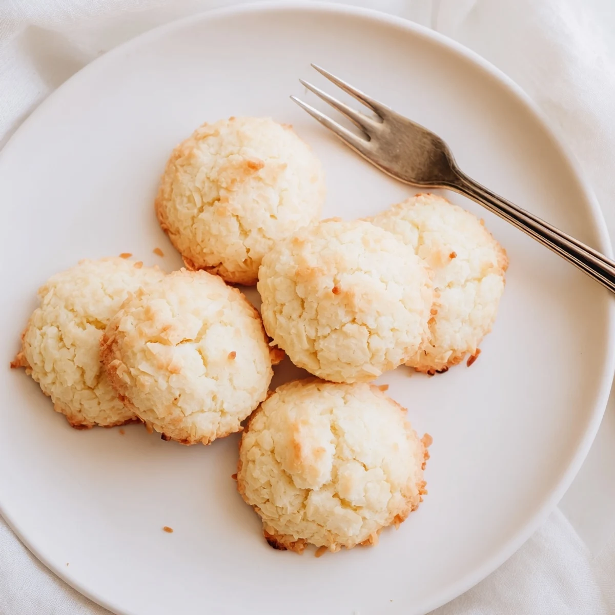 Golden soft and buttery coconut cookies fresh from the oven on parchment paper