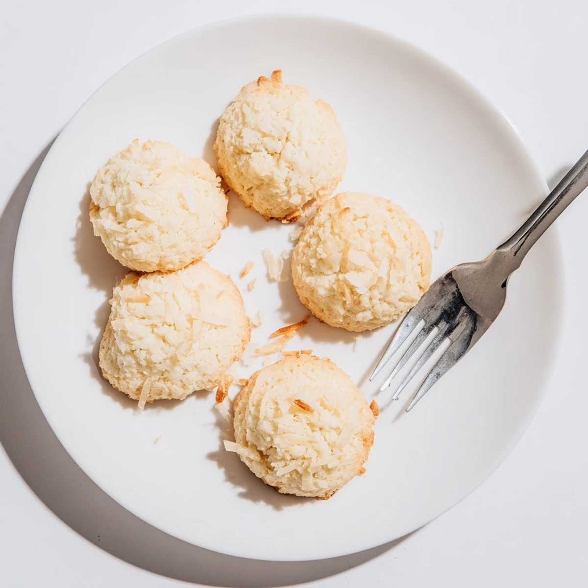 Soft and buttery coconut cookies with crispy edges stacked on a wire rack