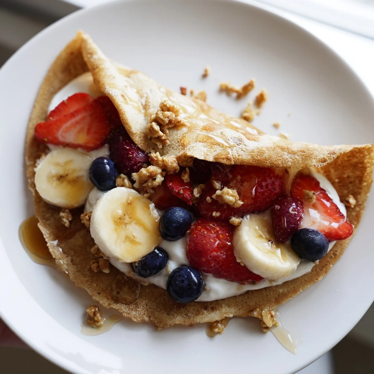 Golden pancake tacos filled with fresh strawberries and drizzled maple syrup on a plate