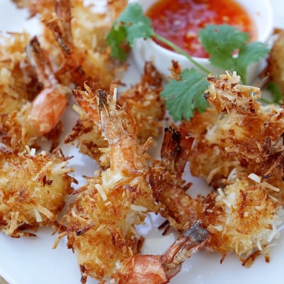 Close-up of golden fried Crispy Coconut Shrimp with Sweet Chili Sauce, highlighting the crunchy coconut crust and tangy dipping sauce.
