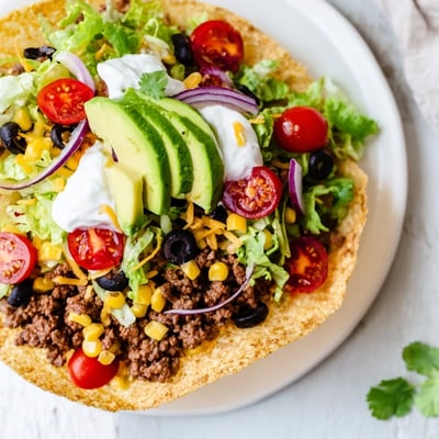 Sliced avocado, sour cream, and salsa top this hearty Beef Taco Salad, served fresh with lime for a zesty finish.