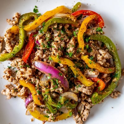Sautéed ground turkey with vibrant bell peppers, garlic, and fresh parsley garnish, ready to serve from a black skillet.