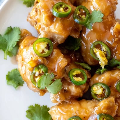 Tender jalapeño peach glazed chicken served with fresh peach slices and cilantro garnish.